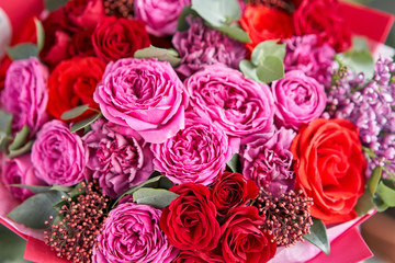 Closeup Bright berry color, Beautiful bouquet of mixed flowers in womans hands. the work of the florist at a flower shop. Delivery fresh cut flower. European floral shop.