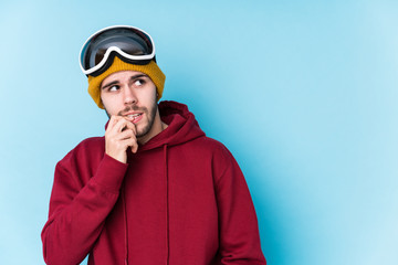 Young caucasian man wearing a ski clothes isolated relaxed thinking about something looking at a copy space.