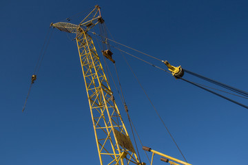 Naklejka premium Construction crane on blue sky background. Lifting construction mechanism