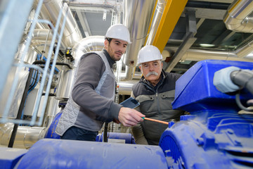 two workers next to an industrial steam boiler