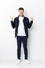 Full body young caucasian man isolated showing rock gesture with fingers