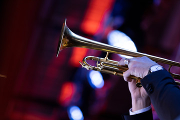 Lead trumpet player in a big band playing a solo in moody stage lighting