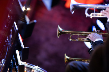 Fototapeta premium Two trumpet players playing their instrument in the trumpet section of a big band during a concert with various color stage lights