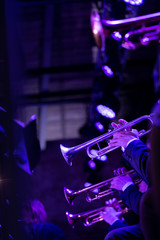  The trumpet section of a big band is playing a chorus during a concert on stage in purple stage lights © Janisphoto