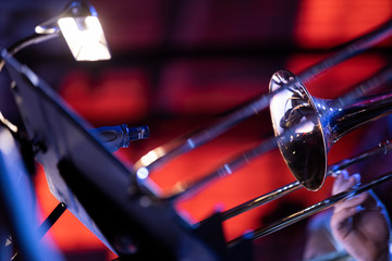 A musician playing the trombone in a big band in moody stage lighting