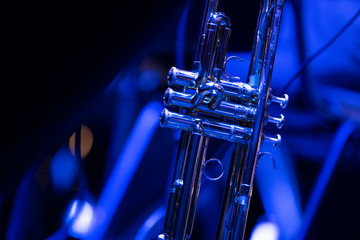 A lacquered trumpet resting in the trumpet section of a big band in blue stage lights