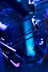 Members of a trombone section in a big band playing some smooth jazz in a venue with blue lights filling the room