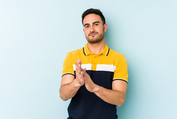 Young caucasian man isolated on blue background feeling energetic and comfortable, rubbing hands confident.