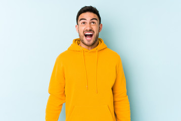 Fototapeta premium Young caucasian man isolated on blue background shouting very angry, rage concept, frustrated.