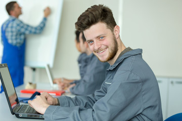 young man in overalls using laptop during training course