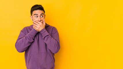 Obraz premium Young caucasian man isolated on yellow bakground thoughtful looking to a copy space covering mouth with hand.