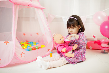 toddler girl pretend play baby care at home against white background