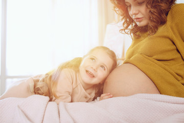 Obraz na płótnie Canvas Pregnant mom plays with her daughter. Concept of family, joy and pregnancy