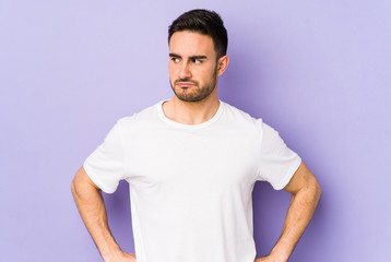 Young caucasian man isolated on purple background confused, feels doubtful and unsure.