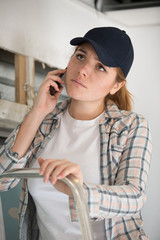 woman contractor worker on the phone on a ladder
