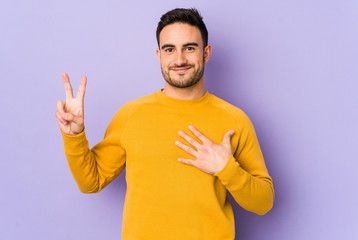 Fototapeta premium Young caucasian man isolated on purple background taking an oath, putting hand on chest.