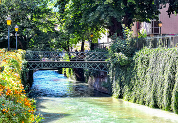 Fototapeta na wymiar Annecy, France-September 4, 2019: View of the river Thiou, a small steel bridge crosses it.
