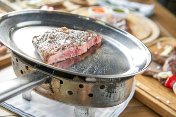 Grilled striploin steak. The strip steak or New York strip On a metal plate with coal. Barbecue restaurant menu.