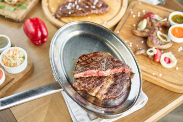 Grilled striploin steak. The strip steak or New York strip On a metal plate with coal. Barbecue restaurant menu.