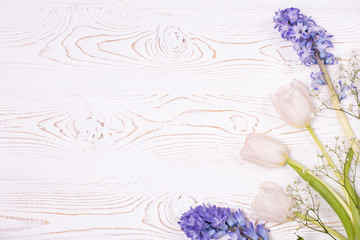 Top view on blue hyacinth flowers and white tulips on a white wooden table with space for text