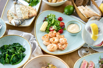 Many different delicious dishes dishes on the table. Various snacks and antipasti on the table. Plates seafood BBQ with garnish. Variety of dishes on the table. Restaurant menu.