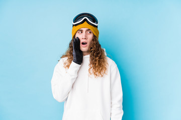 Young caucasian man wearing a ski clothes isolated  is saying a secret hot braking news and looking aside