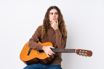 Young caucasian man playing guitar isolated looking sideways with doubtful and skeptical expression.