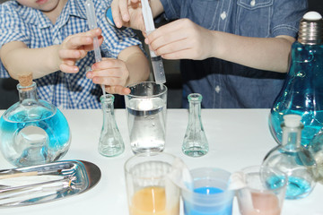 children, elementary school boys, conduct chemical experiments with colored liquids in glass flasks, a scientific concept. 4k slow-motion shooting