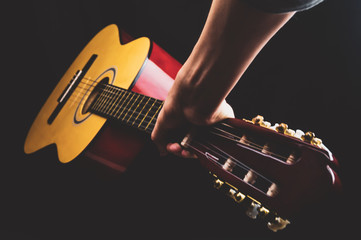Hand holds guitar. acoustic musical instrument on black background