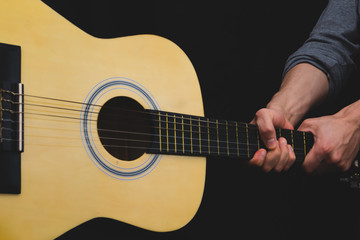 Obraz na płótnie Canvas Hands holds acoustic guitar. musical instrument. black background