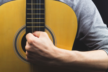 Man holds acoustic guitar. string instrument close up