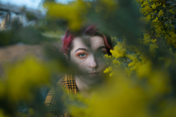 woman with green eyes peeking through yellow folaral bloom