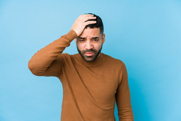 Naklejka premium Young latin man against a blue background isolated tired and very sleepy keeping hand on head.
