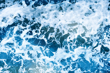 Aerial view of salt ocean foam and waves. Blue water aqua sea background ot texture. Rippled spashing wave.