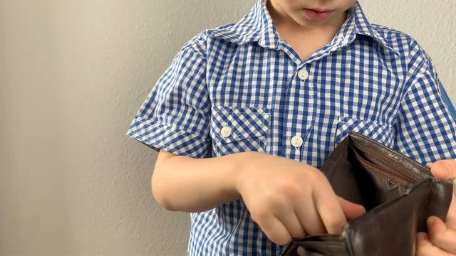 kid is holding a brown wallet in his hand, looking for money and sees that it is empty, the concept of pocket money, theft, shopping