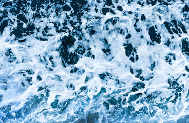 Background shot of aqua sea water waves surface. Blue ocean water and foam aerial or drone photo.