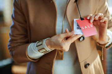 Closeup on woman trying coat and looking at red sale price tag