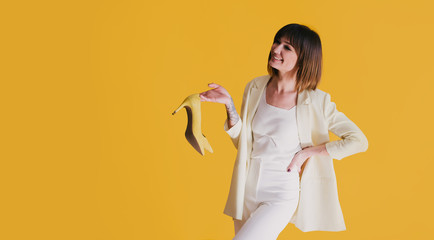 Woman with shoes on yellow background. Copy space.