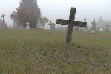 As simple wooden cross marking a lonely grave remote from the rest of the headstones.  The setting...