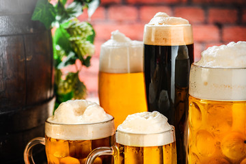 Beer glass and old vintage beer barrel with wheat on wooden table in a alcohol cellar. Beers prepared in various glasses on board.