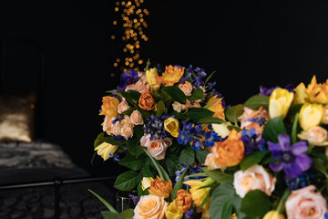 large bouquets of Ranunculus flowers, blue dolphinium, blue muscari, anemone, rose shimmer, yellow tulip by the black bed