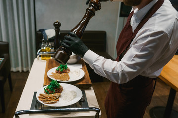 Chef seasoning dishes with a pepper mill