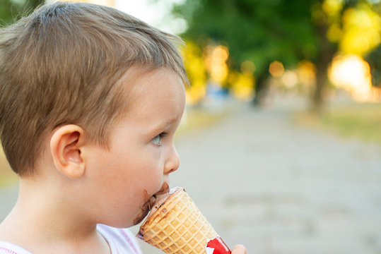Cute Toddler boy eating ice-cream. Kid with dirty face eating ice cream. Happy kid boy eating ice cream