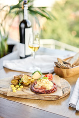 Roasted octopus BBQ and Baked potato with a glass of Grapa. Wooden plate. Restaurant menu