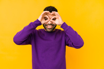 Young mixed race arabic man isolated showing okay sign over eyes