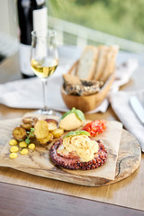 Roasted octopus BBQ and Baked potato with a glass of Grapa. Wooden plate. Restaurant menu