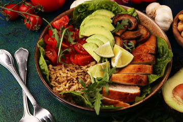 Healthy salad bowl with quinoa, tomatoes, chicken, avocado, lime and mixed greens and mushrooms