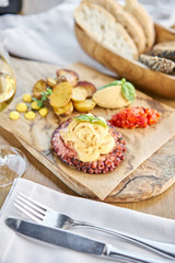 Roasted octopus BBQ and Baked potato with a glass of Grapa. Wooden plate. Restaurant menu