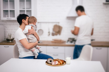 father preparing a baby breakfast with milk in a white kitchen