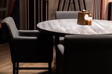 Grey chairs at wooden table in minimalist dining room interior with poster and window. hipster style cafe interior, circle table with napkins and empty chair. Interior concept